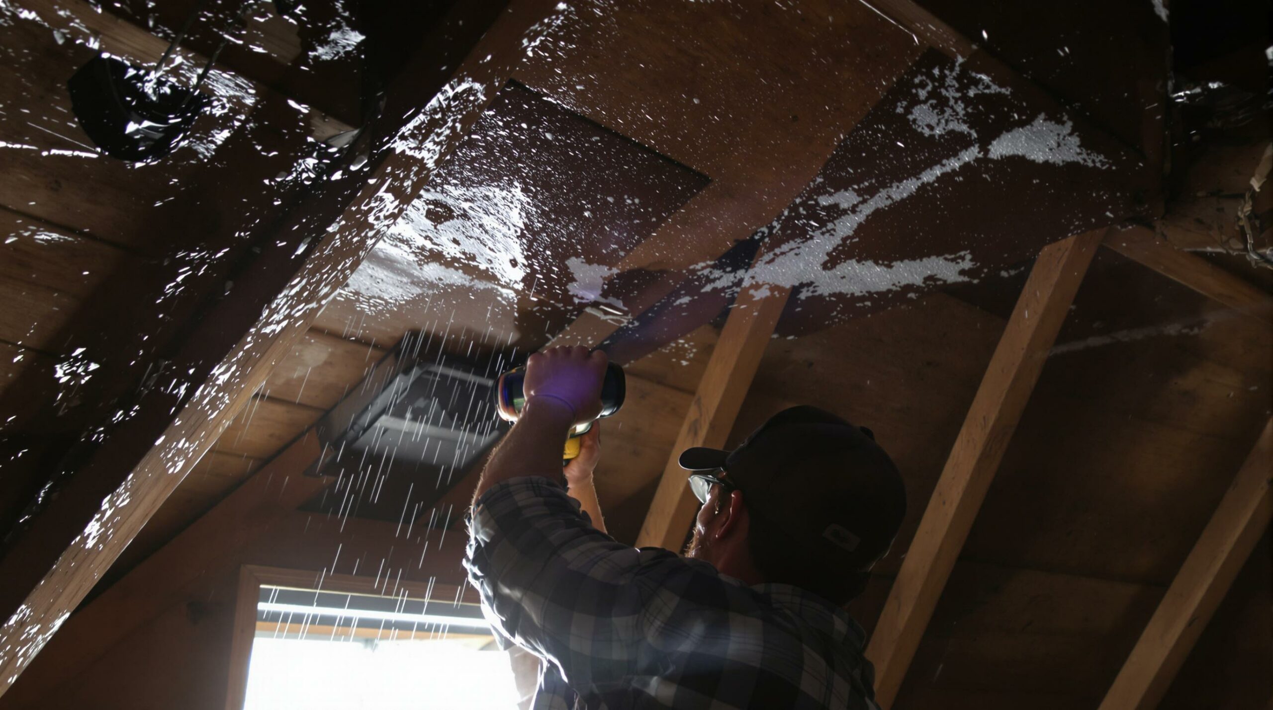 Man spraying insulation in attic